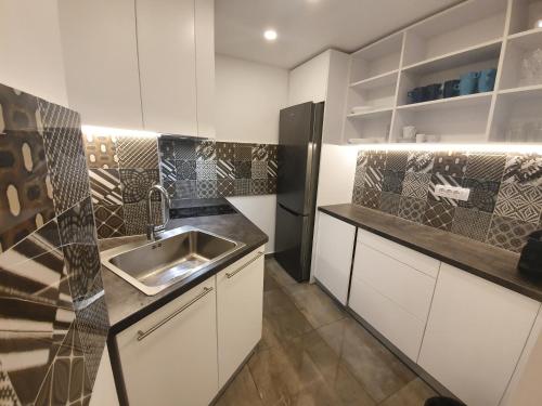 uma cozinha com armários brancos e um lavatório em Premium Crown Suites em Belgrado