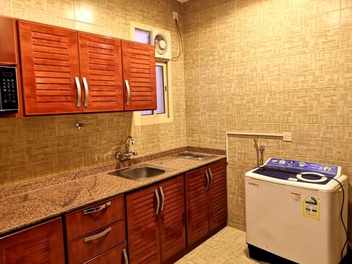 una pequeña cocina con fregadero y lavavajillas en Bzul For Furnished Apartments, en Riad