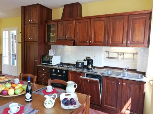 a kitchen with wooden cabinets and a table with a bowl of fruit at Case Vacanze Borgo Faraldi in Villa Faraldi