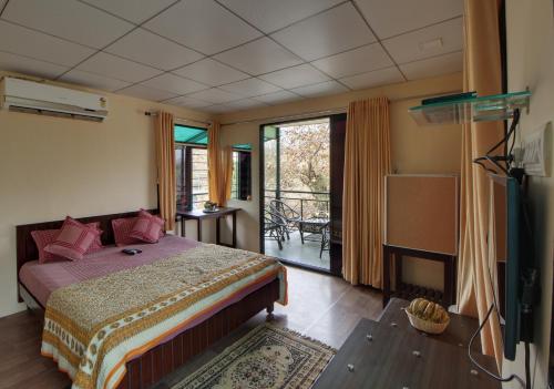 a bedroom with a bed and a balcony at Gir Pride Resort in Sasan Gir