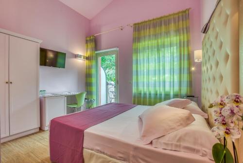 a bedroom with a bed with pink walls and a window at Hotel Des Reves in SantʼElia Fiumerapido