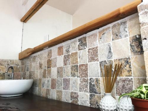 a bathroom with a sink and a tile wall at Casa Mediterana in 2 Mai