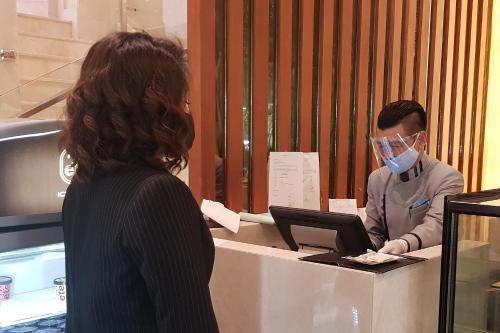 a woman wearing a face mask standing at a cash register at Royal Princess Larn Luang - SHA Extra Plus in Bangkok