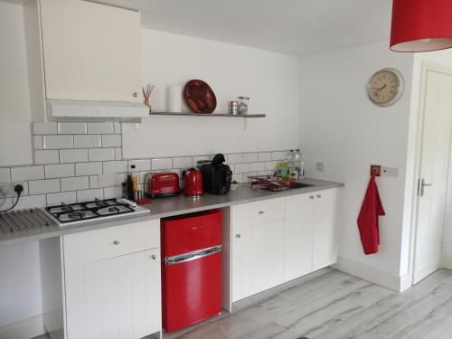 a kitchen with a red refrigerator and white cabinets at Pier Road Cottage, Croagh Patrick in Westport