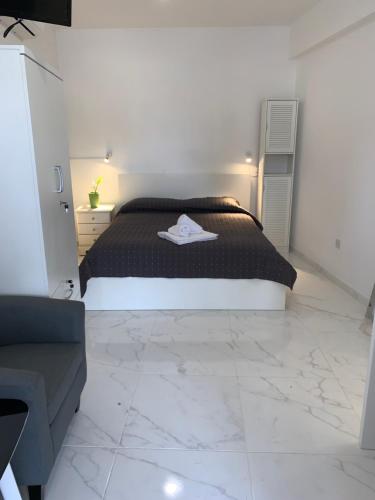 a bedroom with a black bed and a white tile floor at Jacks Apartment in Paphos City