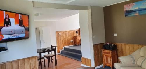a living room with a couch and a tv on the wall at Cradle Alpine Retreat in Moina