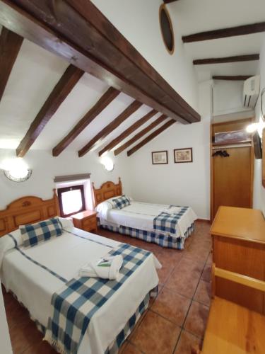 a room with two beds and a desk in it at Complejo La Veguilla in Arroyo del Ojanco