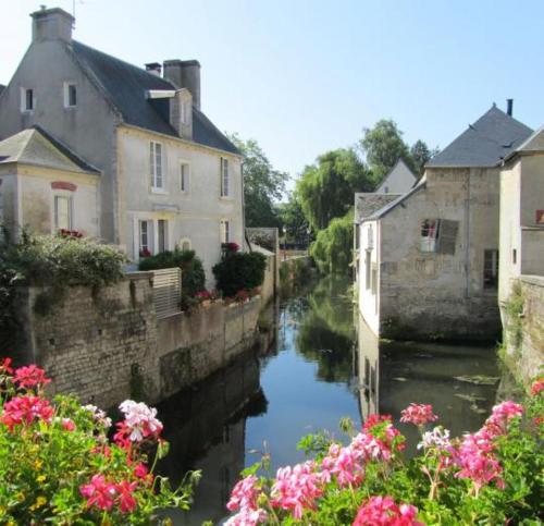 une rivière avec des maisons et des fleurs dans une ville dans l'établissement Camping du Creulet, à Crouay