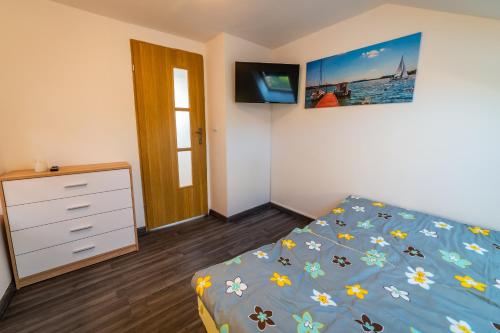 sypialnia z łóżkiem, komodą i telewizorem w obiekcie Apartament Nad Jeziorem Mikołajki w mieście Mikołajki