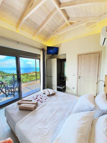 a bedroom with a large bed with a large window at euphoria villas - Gaia & Aura in Agios Nikitas