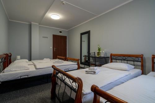 a room with four beds with white sheets at Noclegi Stop and Sleep Zgorzelec in Zgorzelec