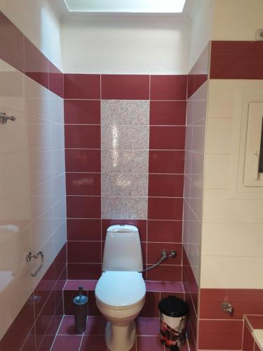a bathroom with a toilet and red tiles at Aegean View Seaside Apartment in Kavala