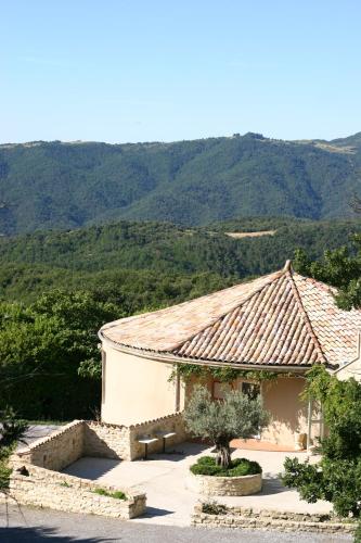 a building with a roof with mountains in the background at Domaine Plein Sud in Bruzac