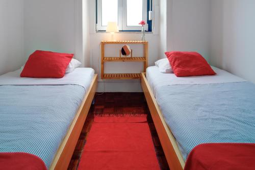 2 bedden met rode kussens in een kamer bij Janelas Do Tejo in Lissabon