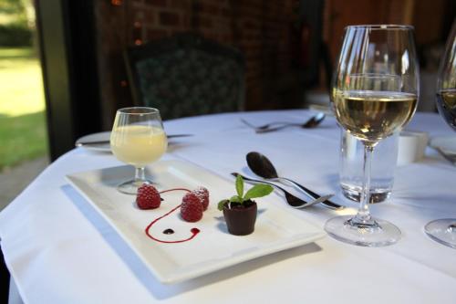 a table with a plate with strawberries and a glass of wine at Ivy House Country Hotel in Lowestoft