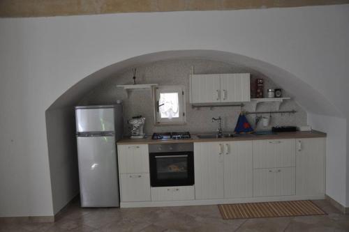 a kitchen with white cabinets and a white refrigerator at La Sassolina appartamento in Matera