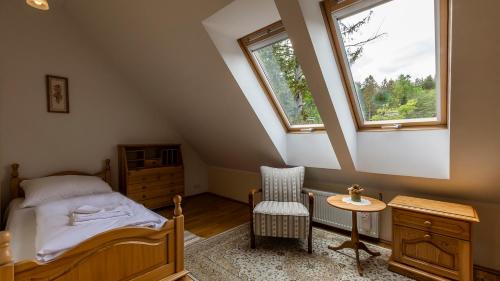 a attic bedroom with a bed and a chair at VacationClub – Okrzei 1B Apartament 19 in Karpacz