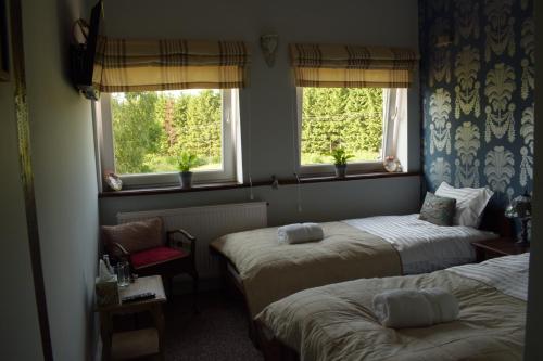 twee bedden in een kamer met twee ramen bij Zakątek Warmiński in Płoskinie