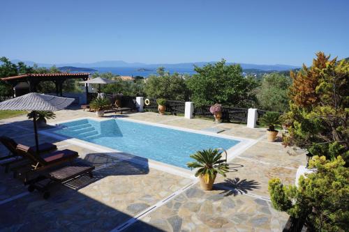 basen na dziedzińcu z krzesłami i drzewami w obiekcie Villa Pefka w mieście Skiatos
