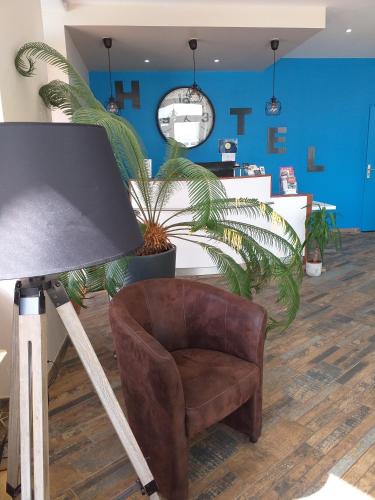 a chair in a room with a blue wall at Hôtel La Couronne in Marmande