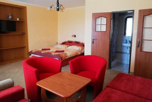 Krásnohorské PodhradieにあるUbytovanie Bettyのベッドルーム1室(ベッド1台、赤い椅子、テーブル付)