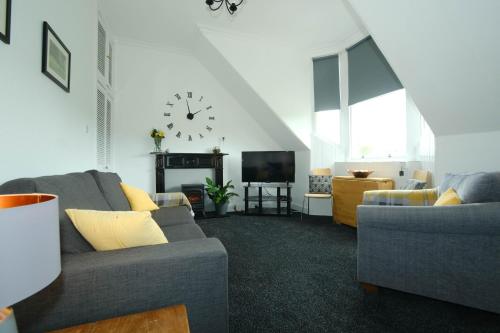 a living room with a couch and a clock on the wall at Marys Garden View North in Jedburgh