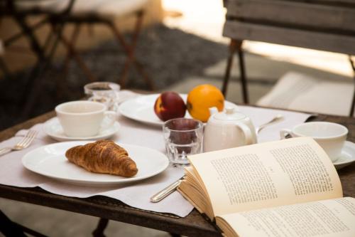 a table with a book and a plate with a croissant on it at Riva Lofts Florence in Florence