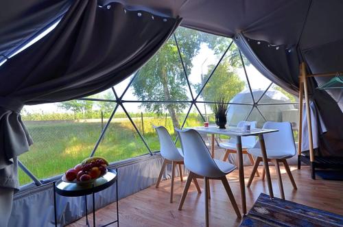 une chambre avec une table et des chaises dans une tente dans l'établissement Slowly Glamping Osada Nad Wodą, à Łazy
