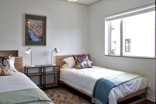 a bedroom with two beds and a window at Table Mountain views, modern,lots of natural light, with parking in Cape Town