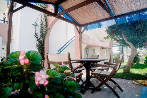 - une terrasse avec une table, des chaises et des fleurs dans l'établissement Marika Apartments, à Mastichari