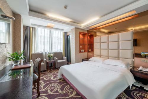 a hotel room with a large bed and a desk at Yiwu Yuejia Business Hotel in Yiwu