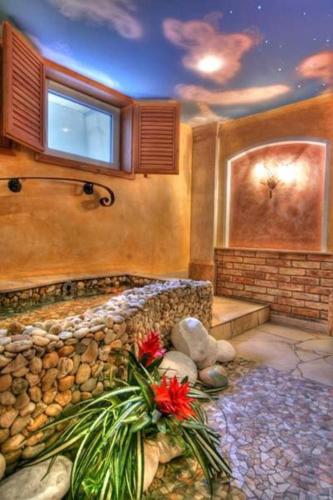 a room with a bath tub with a stone wall at Villa Medici Hotel & Restaurant in Veszprém