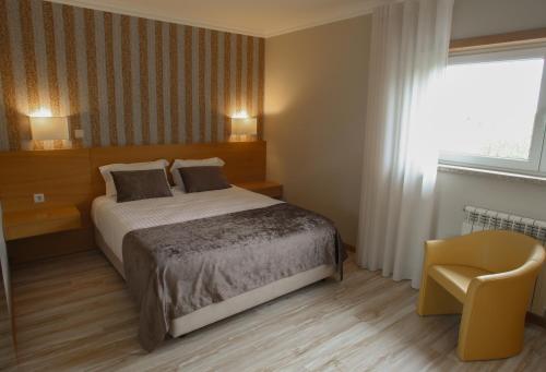 a bedroom with a bed and a chair and a window at Paraiso Douro in Lamego