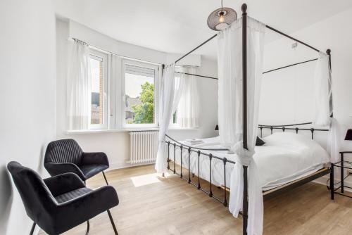 een slaapkamer met een hemelbed en een stoel bij Holiday house Villa Victoria in Diksmuide