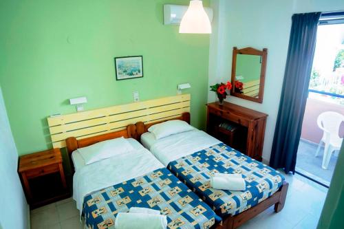 a bedroom with two beds and a mirror and a window at Marika Apartments in Mastichari