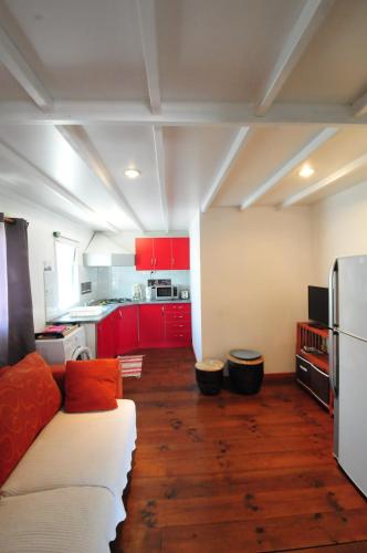 a living room with a couch and a kitchen with red cabinets at SAS L' Ilot Vert in La Saline les Bains