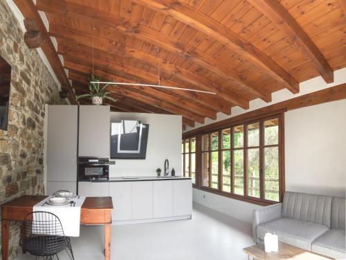 uma cozinha com armários brancos e um tecto de madeira em Casa Rural Madariaga em Artea