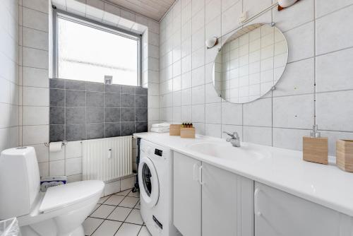 a white bathroom with a sink and a washing machine at Hvide Sande Hotel in Hvide Sande