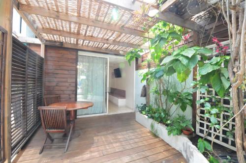 an outdoor patio with a wooden table and a pergola at SAS L' Ilot Vert in La Saline les Bains