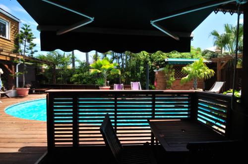 a swimming pool with a table and chairs and an umbrella at SAS L' Ilot Vert in La Saline les Bains