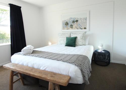 a bedroom with a large bed and a wooden bench at 1 - Delightfully fresh, private home close to town in Wanaka