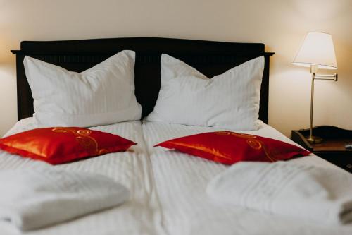 a bed with red and white pillows on it at Páva City in Odorheiu Secuiesc
