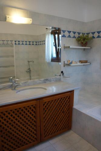 a bathroom with a sink and a tub and a mirror at Villa Pefka in Skiathos