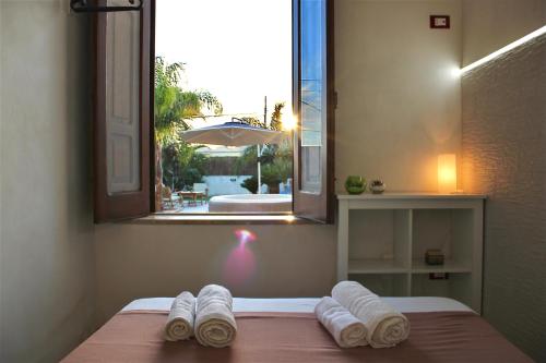 a bedroom with a bed with towels on it with a window at Terre di Sicilia in Marsala