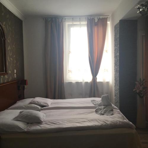 a bed in a bedroom with a window at Európa Panzió in Mátészalka