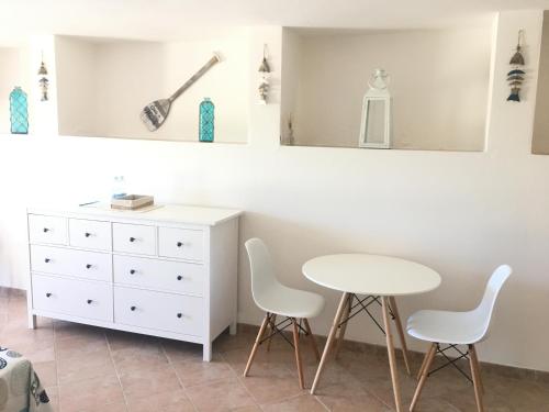 - une chambre avec une table blanche, des chaises et une commode dans l'établissement B&B Tavolara, à Puntaldia
