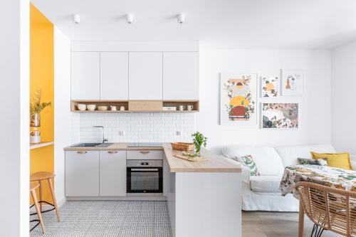 a kitchen with white cabinets and a white couch at Blue Mandarin Garden Gates in Gdańsk
