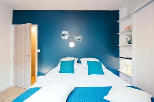 ein blaues Schlafzimmer mit einem weißen Bett und blauen Kissen in der Unterkunft The Rhuys - Cosy-balcony with superb Loire view - all on foot - Parking in Nantes
