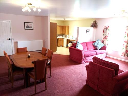 a living room with a table and a pink couch at Mellwaters Barn Cottages in Bowes