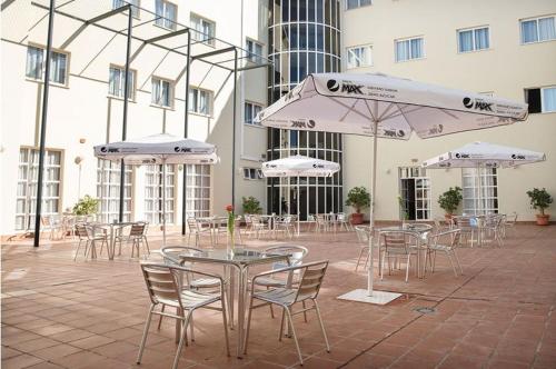 een patio met tafels en stoelen en witte parasols bij Ele Andarax in Aguadulce